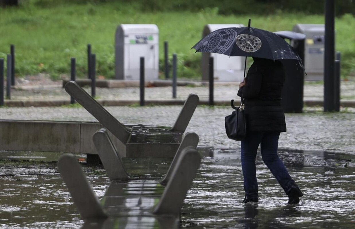Mulher a caminhar com um guarda-chuva aberto