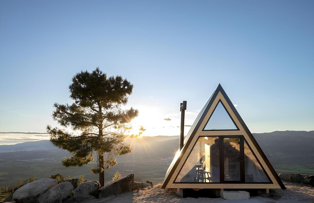 Uma casa triangular construída no topo da montanha ao nascer do sol
