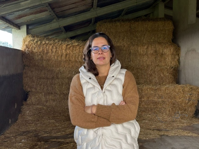Fotografia de frente de Joana Vacas Freixa na sua exploração com fardos de palha atrás de si