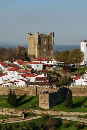 Imagem aréa da paisagem de Bragança, onde se vê o castelo, a moralha e vários edifícios, num dia com algumas núvens.