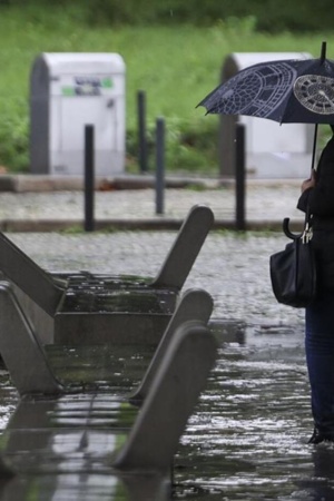 Mulher a caminhar com um guarda-chuva aberto